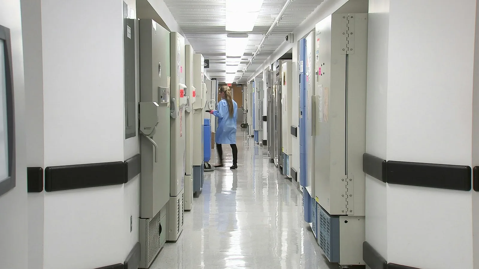A man walking down a long, bright corridor