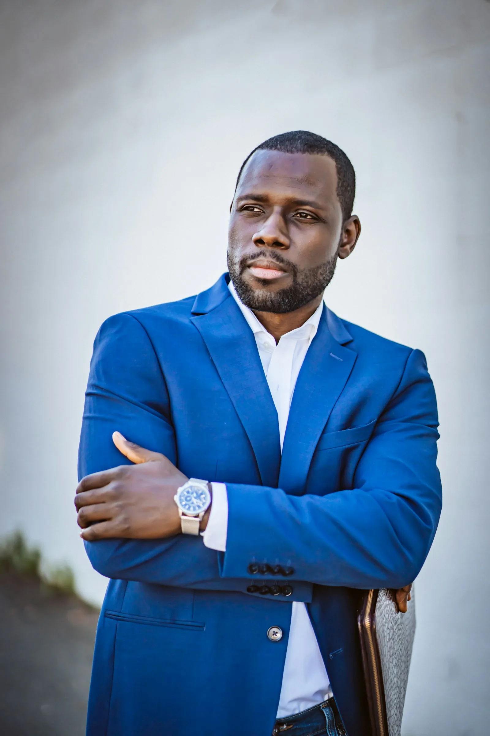 A director in a blue suit, arms folded
