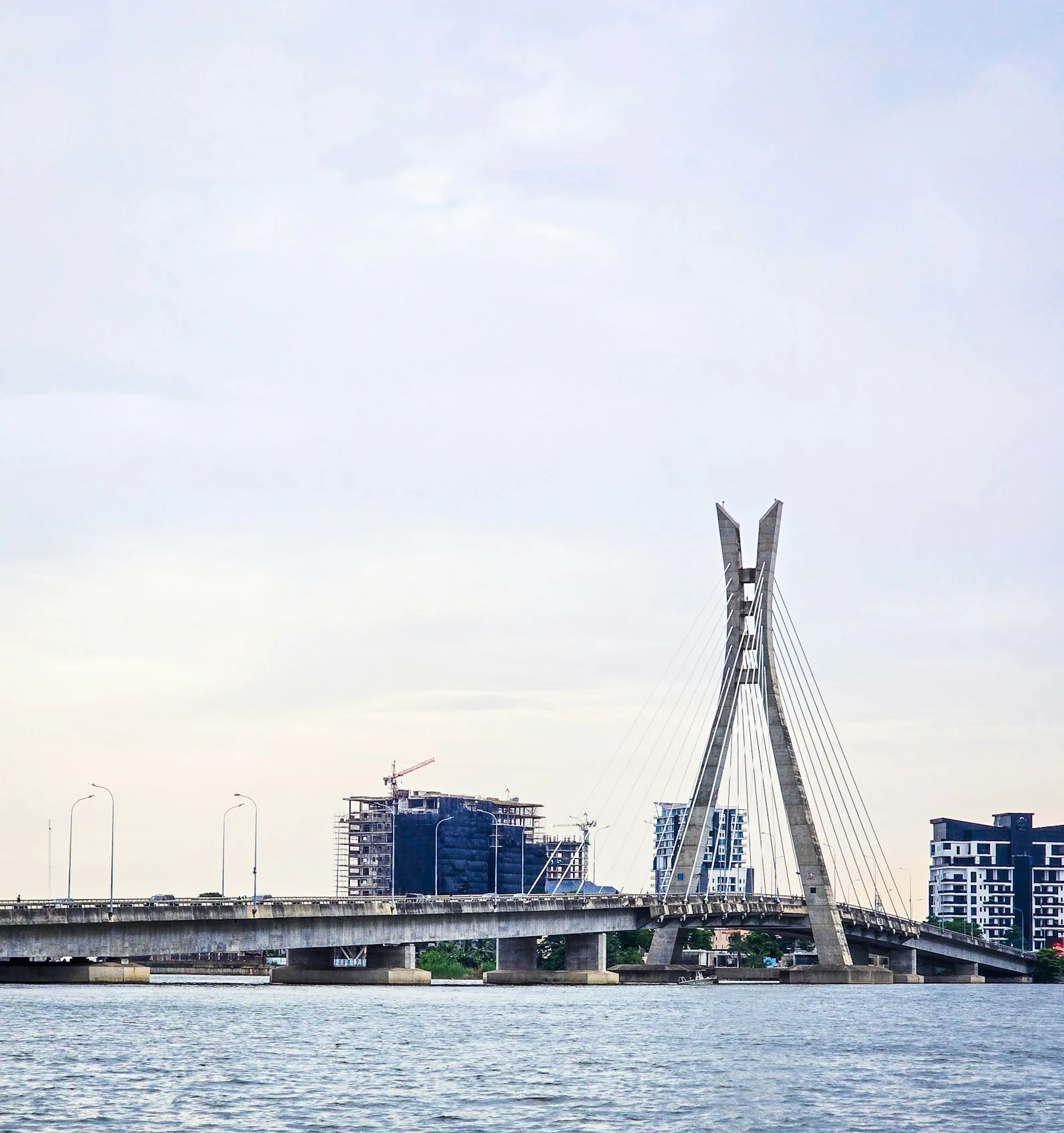 A cable-stayed bridge over a lagoon in Lagos at dusk