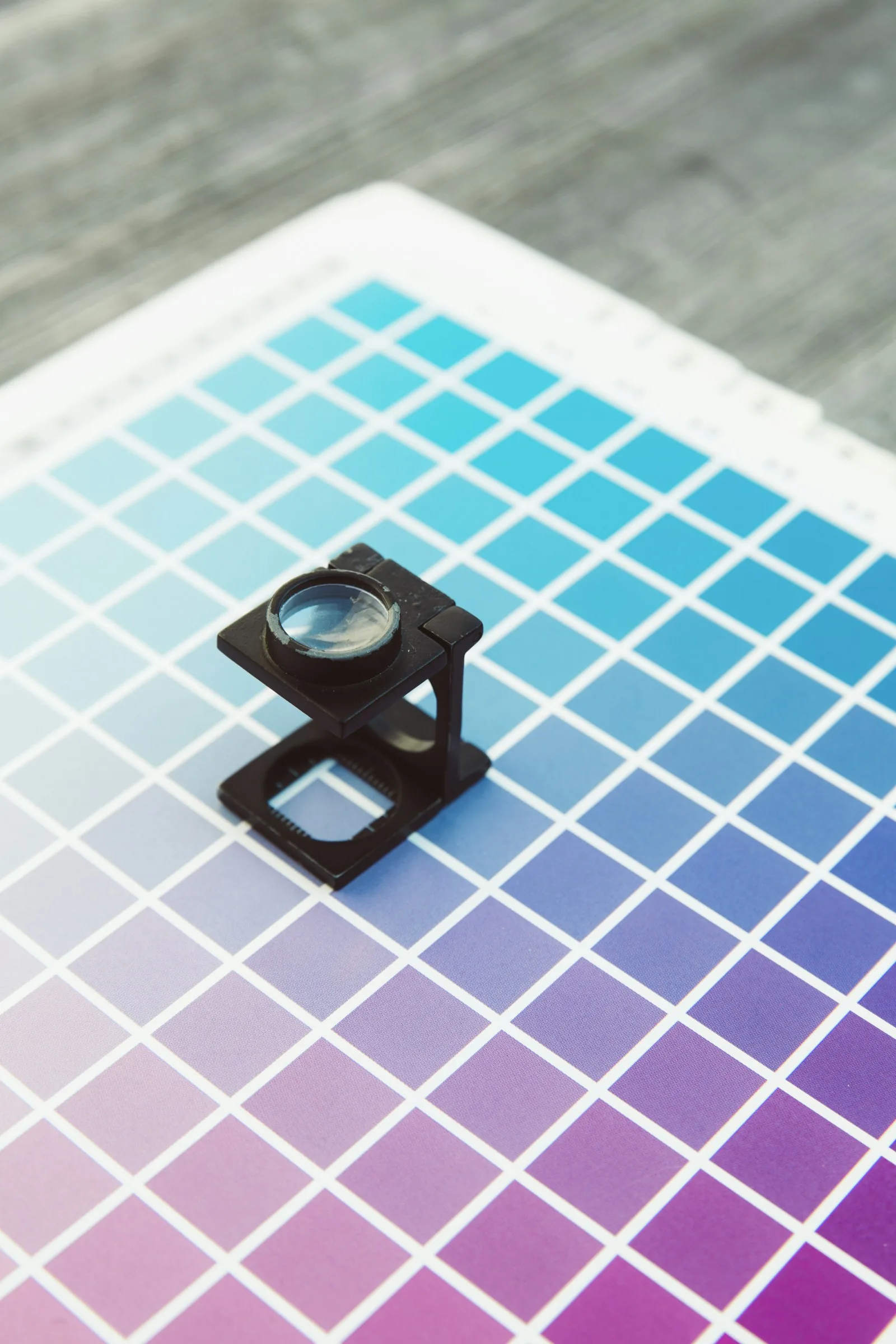 A printer's loupe resting on colour proofs