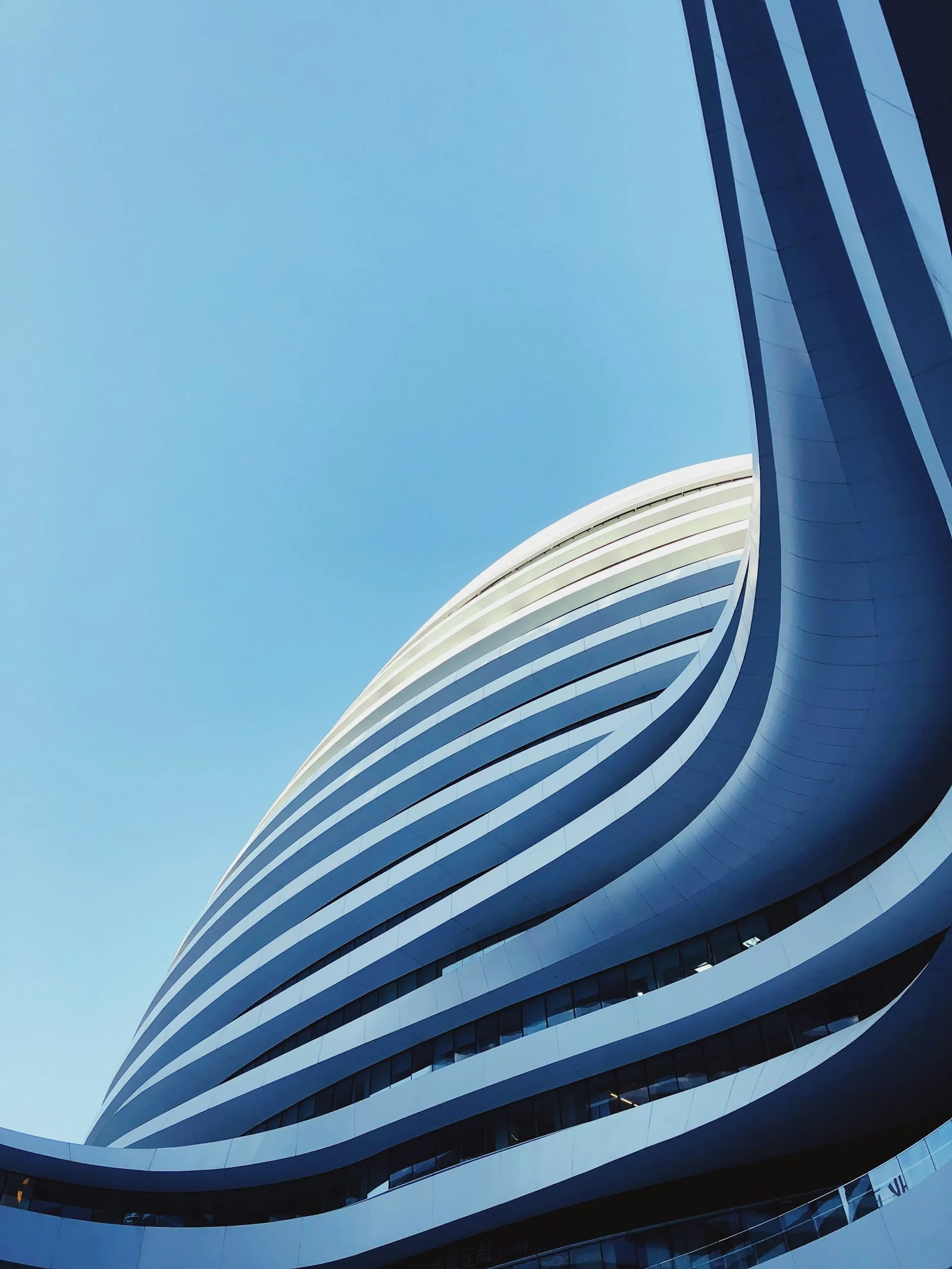 Curving white balconies of a high-rise against blue sky